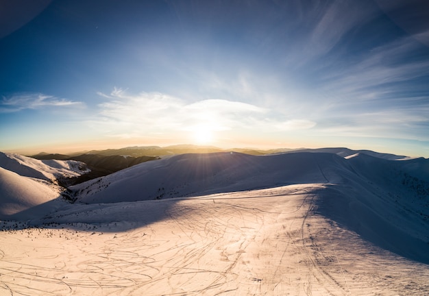 Bovenaanzicht van een prachtig betoverend uitzicht op de skipiste met ski-pistes gelegen in de bergen op een zonnige winterse ijzige avond