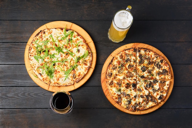 Bovenaanzicht van een tafel met twee pizza's en een glas wijn en bier