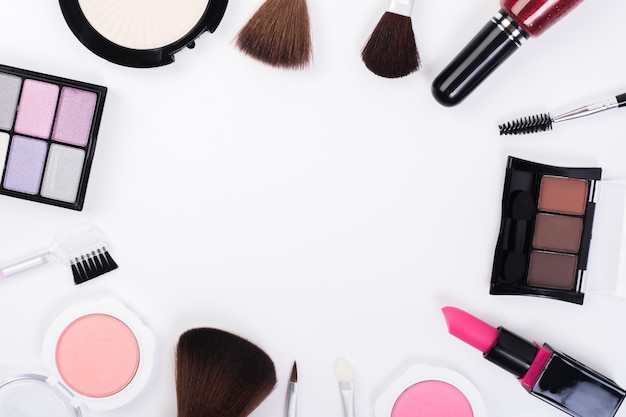 Bovenaanzicht van een verzameling cosmetische schoonheidsproducten die rond een lege ruimte op een witte achtergrond worden geregeld.