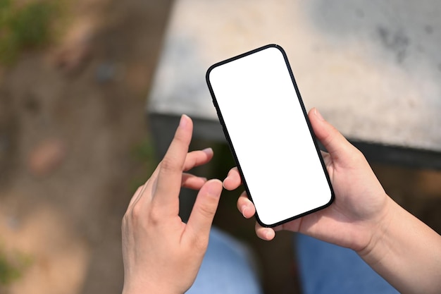 Bovenaanzicht van een vrouw die haar telefoon gebruikt in het park of tuin telefoon wit scherm mockup