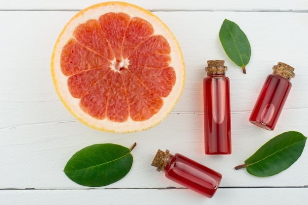 Bovenaanzicht van een witte houten achtergrond met flessen etherische olie van grapefruit en een half stuk grapefruit. natuurlijke biologische producten van zelfzorg.