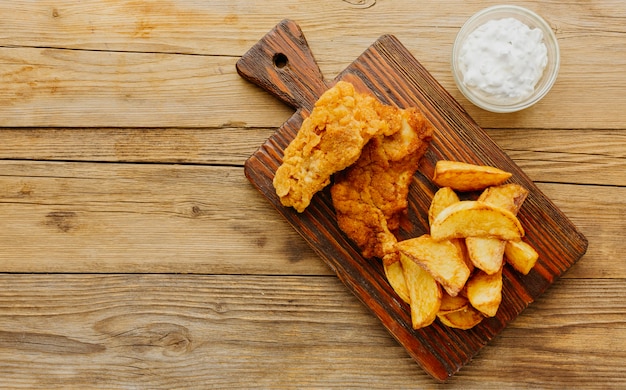 Bovenaanzicht van fish and chips met saus op snijplank