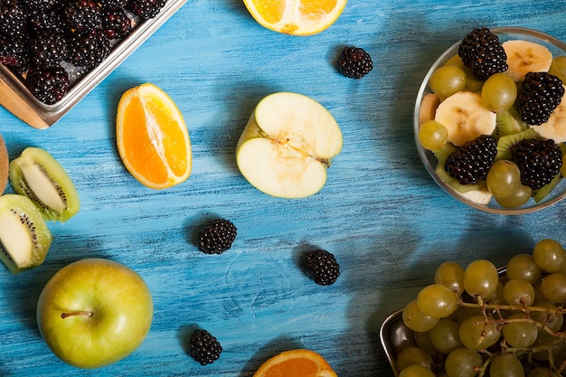 Bovenaanzicht van fruit en barries over een blauw bureau in de studio. Natuurlijke verfrissing tropische voeding