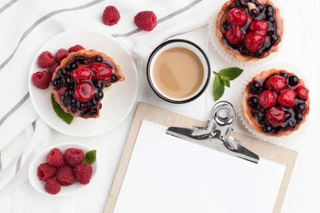 Foto bovenaanzicht van fruittaartjes met kladblok en koffie