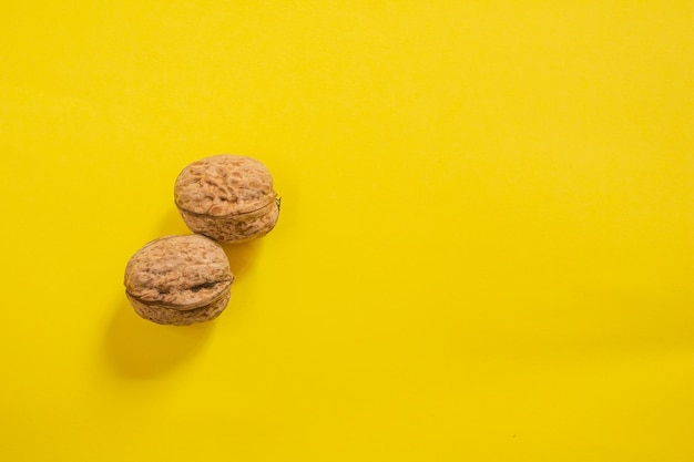 Bovenaanzicht van gedroogde walnoten op gele achtergrond met kopieerruimte