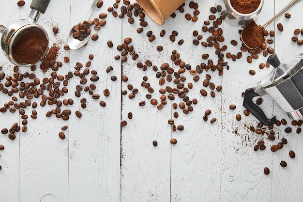 Bovenaanzicht van geiser koffiezetapparaat portafilter lepels en papieren beker op wit houten oppervlak met