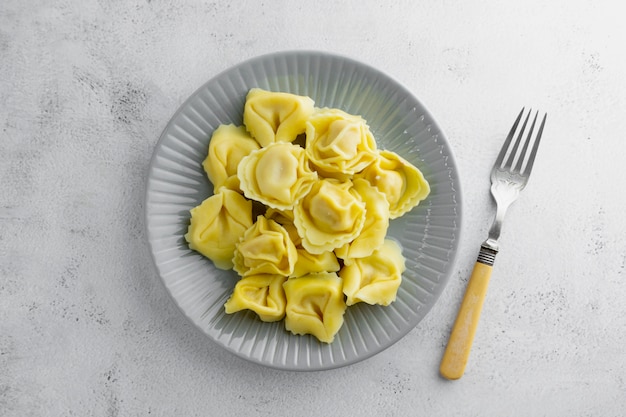 Bovenaanzicht van gekookte tortellini op een plaat, geïsoleerde pastagerecht.