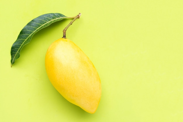 Bovenaanzicht van gele mango op groene achtergrond.