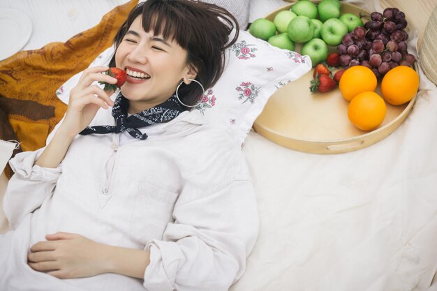 Bovenaanzicht van gelukkige vrouw gaat picknicken en eet aardbei in de tuin