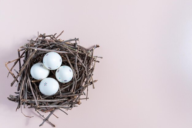 Bovenaanzicht van geschilderde paaseieren in een nest van twijgen op een effen achtergrond