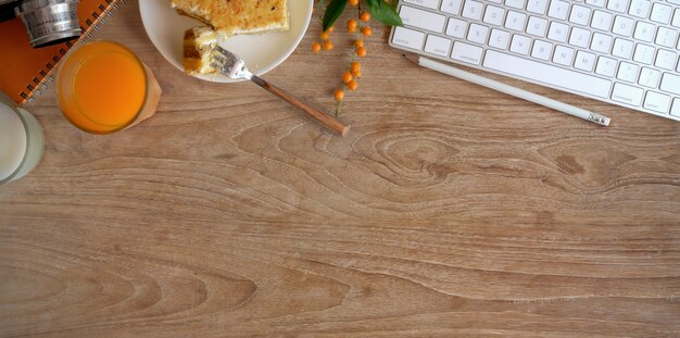 Bovenaanzicht van gezellige werkruimte met een glas jus d'orange en toast brood op houten tafel