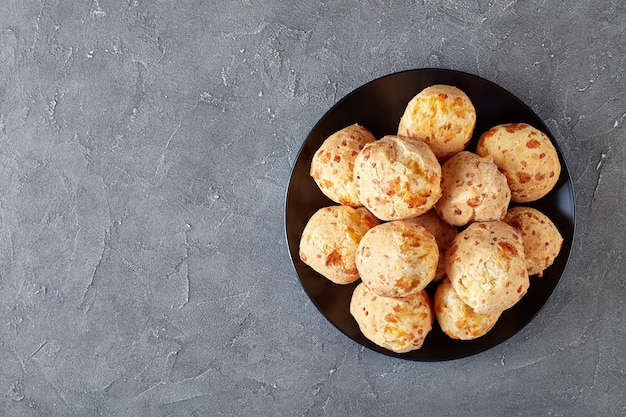 Bovenaanzicht van Gougeres, kaas pufjes ballen op een zwarte plaat. Traditionele Franse kaas choux broodjes op een betonnen tafel, uitzicht van bovenaf, flatlay, close-up, kopie ruimte