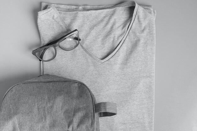 Bovenaanzicht van grijs herenmode t-shirt met grijze bril en een grijze toilettas op grijs