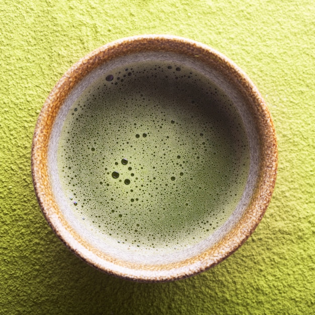 Bovenaanzicht van groene thee matcha in een kom op een gepoederd oppervlak