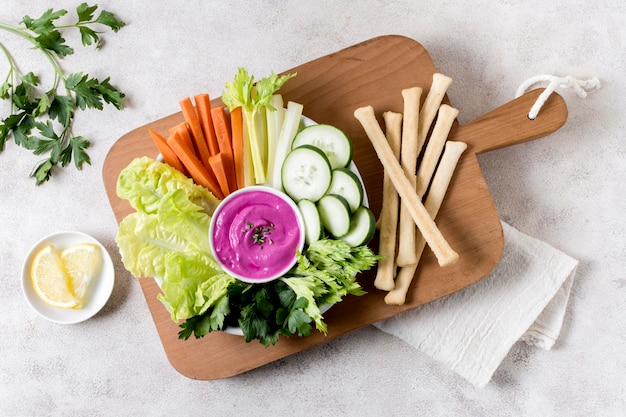 Foto bovenaanzicht van groenten met roze saus op snijplank