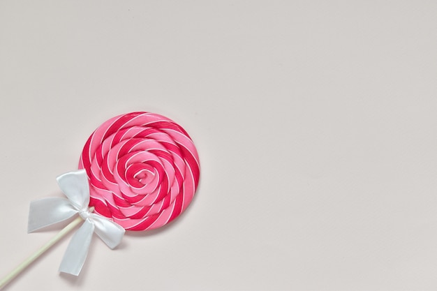 Bovenaanzicht van grote ronde roze lolly met een witte strik