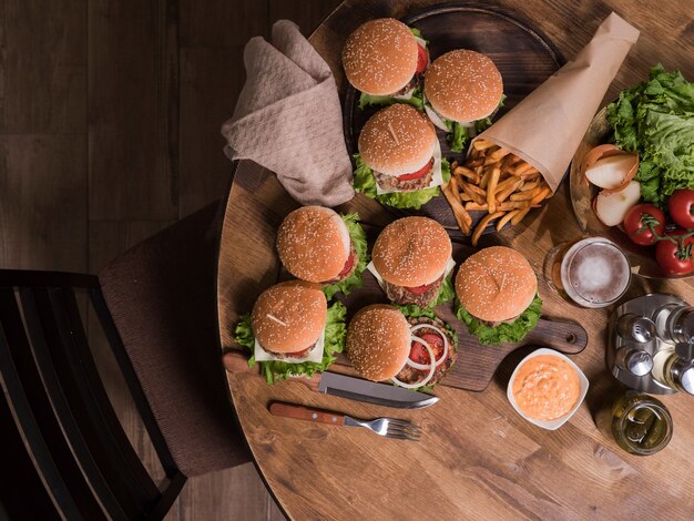 Bovenaanzicht van hamburgers met rundvlees naast frietjes. Houten tafel. Gesmolten kaas.