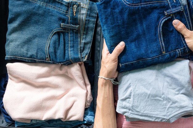 Bovenaanzicht van hand vouwen kleding en jeans, handen vouwen jeans op een grijze achtergrond. conceptuele foto.