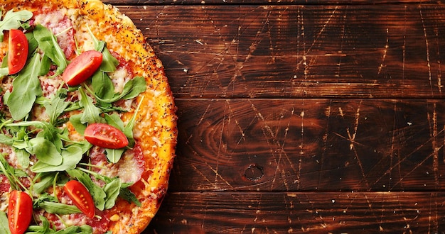 Foto bovenaanzicht van heerlijke italiaanse pizza geserveerd op donkerbruine houten tafel met kopieerruimte