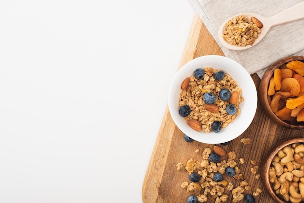 Bovenaanzicht van heerlijke muesli met noten, bosbessen en gedroogde abrikozen geïsoleerd op wit