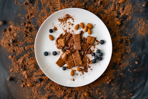 Bovenaanzicht van het dessert met chocoladereep, bosbes, amandelnoten op de witte borden