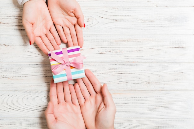 Bovenaanzicht van het geven van een geschenk aan een mooie persoon op houten achtergrond.