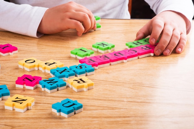 Bovenaanzicht van het leeralfabet van de kindarm met puzzel in de tafel Kopieer de ruimte Leren in de vorm van een spelconcept Eenvoudig leren Studieniveau