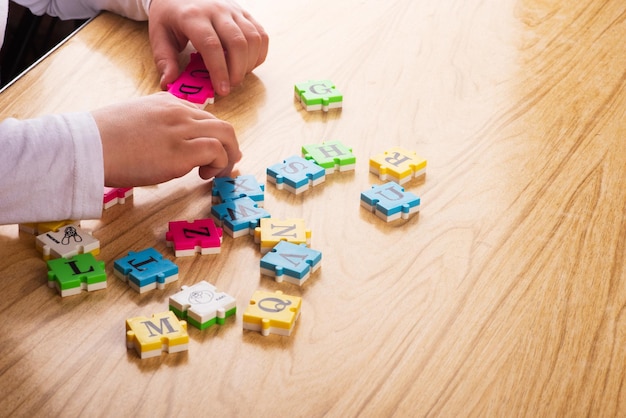 Bovenaanzicht van het leeralfabet van de kindarm met puzzel in de tafel Kopieer de ruimte Leren in de vorm van een spelconcept