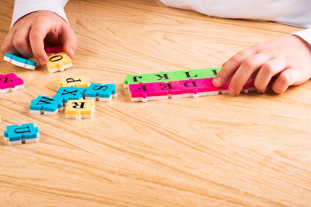 Bovenaanzicht van het leeralfabet van de kindarm met puzzel in de tafel Kopieer de ruimte Leren in de vorm van een spelconcept