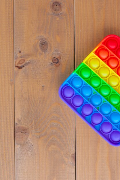 Foto bovenaanzicht van het nieuwe zintuiglijke speelgoed-regenboog pop it. antistress speelgoed voor kinderen en volwassenen. een kleurrijk speelgoed.