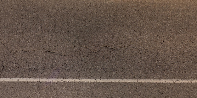 Bovenaanzicht van het oppervlak van asfaltweg gemaakt van kleine stenen en zand met scheuren