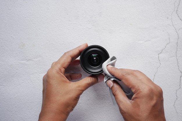 Bovenaanzicht van het schoonmaken van een cameralens met een schoonmaakdoekje