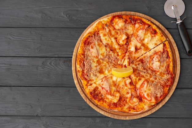 Bovenaanzicht van hete pizza op zwarte houten tafel