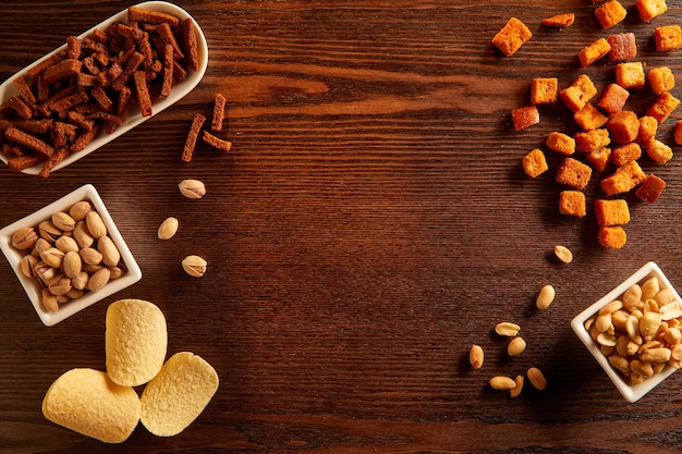 Bovenaanzicht van houten tafel omlijst met snacks, noten en chips kopieer de ruimte