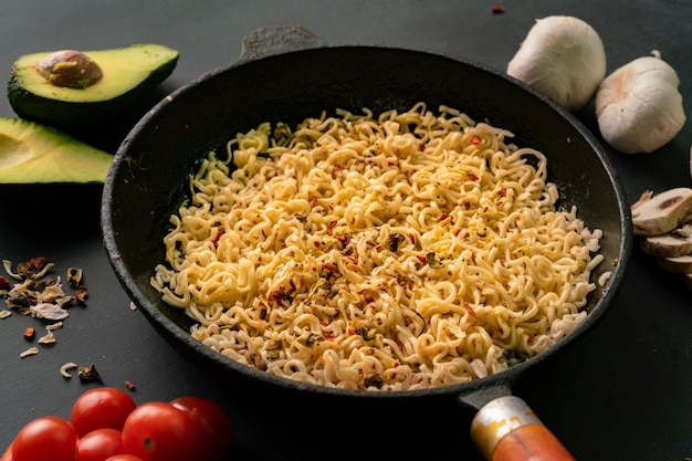 Bovenaanzicht van ingrediënten voor het koken van pasta op tafel, avocado, noedels in de pan, champignons