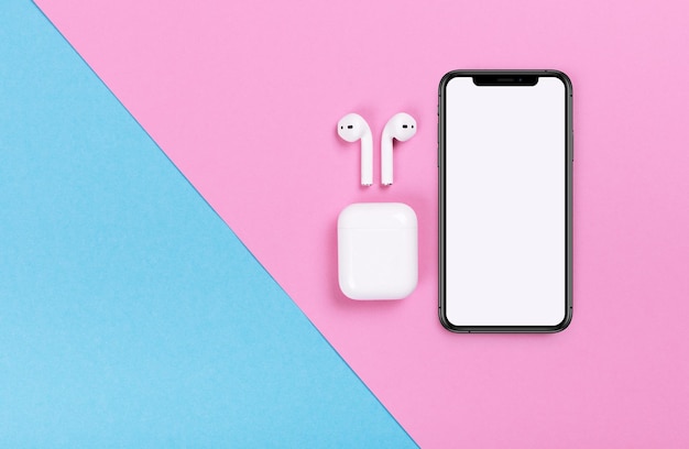 Bovenaanzicht van iphone en Apple AirPods op roze en blauwe achtergrond