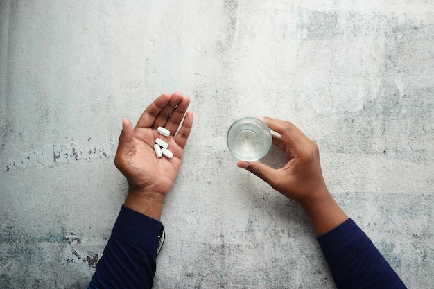 Bovenaanzicht van jonge mannen die een medische pil nemen en een glas water vasthouden