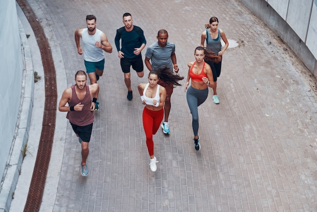 Bovenaanzicht van jonge mensen in sportkleding die joggen terwijl ze buiten sporten