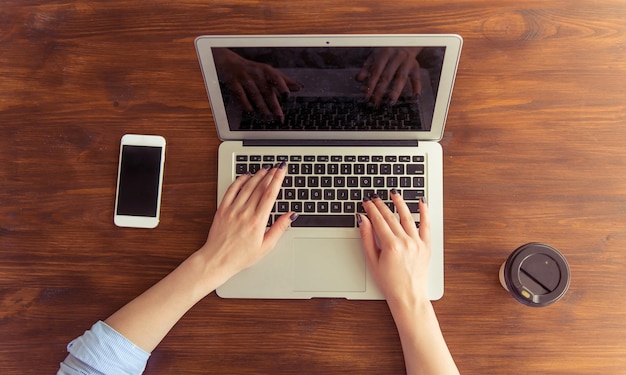 Bovenaanzicht van jonge zakenvrouw die een laptop gebruikt terwijl ze op kantoor werkt