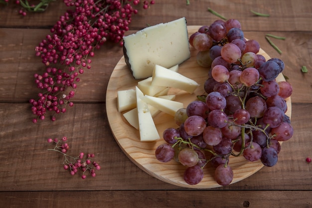 Bovenaanzicht van kaasplateau met druiven op houten tafel