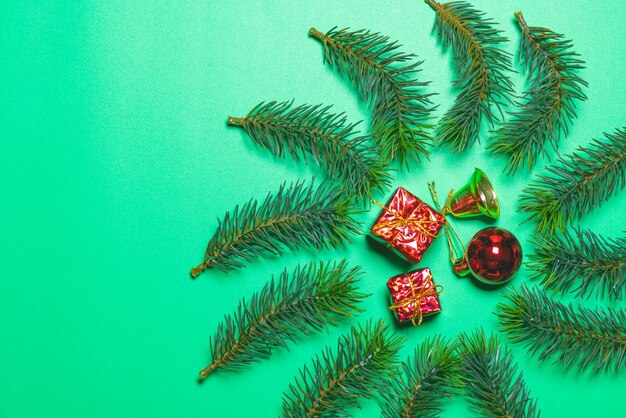 Bovenaanzicht van kerstcadeaudoos rode ballen met vuren takken en bel op groene achtergrond