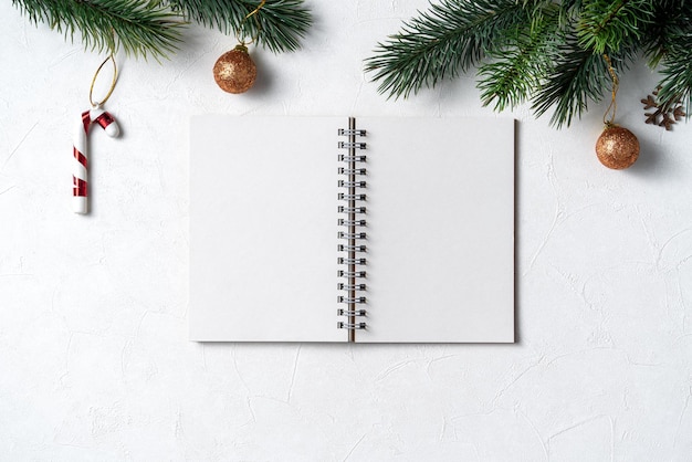 Bovenaanzicht van kerstversiering achtergrond met lege notebook op witte tabelachtergrond met kopie ruimte, concept van vakantieviering.