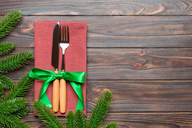 Bovenaanzicht van kerstversiering op houten achtergrond. De vork en het mes op servet klopten met lint en lege ruimte. Nieuw jaarpatroon