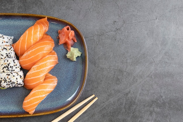 Bovenaanzicht van klassieke sushi rolletjes met zalm nigiris wasabi gember en eetstokjes met kopieerruimte