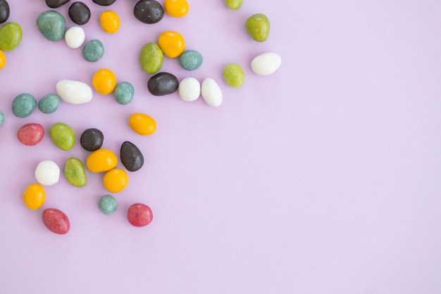 Bovenaanzicht van kleurrijke snoepjes op violette achtergrond met kopieerruimte