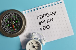 Bovenaanzicht van klokkompas en wit papier geschreven met hashtag dream plan en do