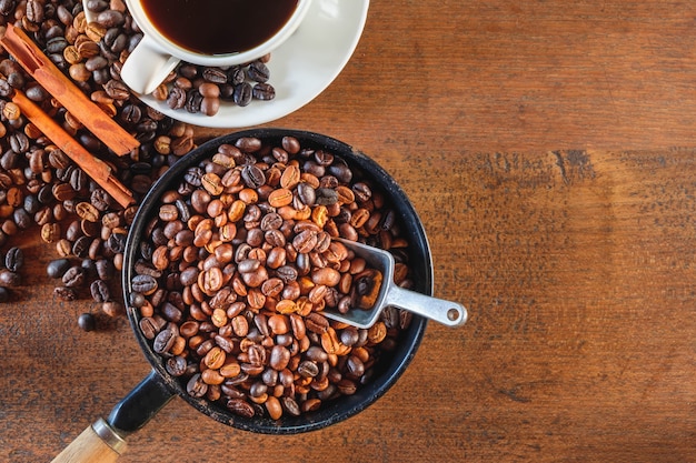 Bovenaanzicht van koffiebonen geroosterd in een pan en een koffiekopje.