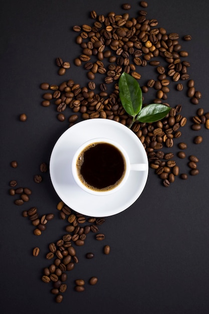 Bovenaanzicht van koffiekopje en koffiebonen op de zwarte achtergrond. Detailopname.