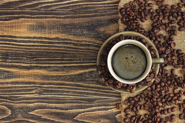 Bovenaanzicht van koffiekopje met koffiebonen en kopie ruimte