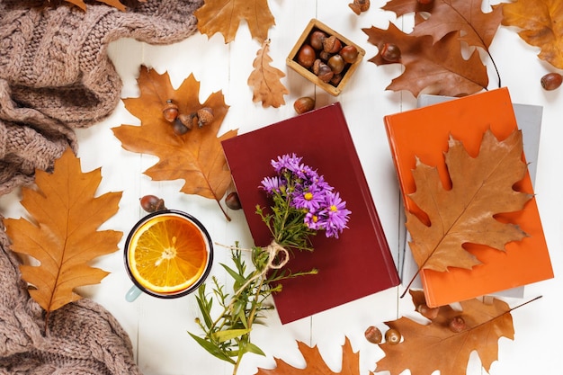 Bovenaanzicht van kopje thee met oranje herfstbladeren een warme sjaal op houten achtergrond